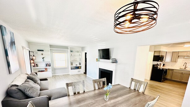 A modern living room with a dining table, sofas, and a fireplace. - Spacious 4-BR, 2.5 Bath vacation home: Foosball, 65" TV, Golf, 4 Season Room (Sioux Falls)