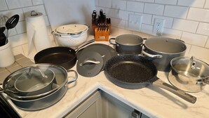 A kitchen with various pots and pans on the counter, a colander, and a set of knives in a holder. - Spacious 4-BR, 2.5 Bath vacation home: Foosball, 65" TV, Golf, 4 Season Room (Sioux Falls)