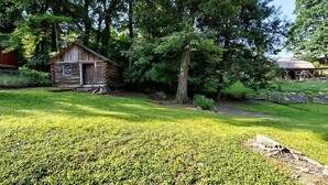 Un chalet rustique aux murs en bois, entouré d’une végétation luxuriante et d’arbres.