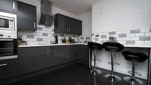 A modern kitchen with dark cabinets, a stainless steel oven, and a black countertop.