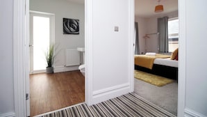 A room with a bed, a radiator, a potted plant, and a painting on the wall.