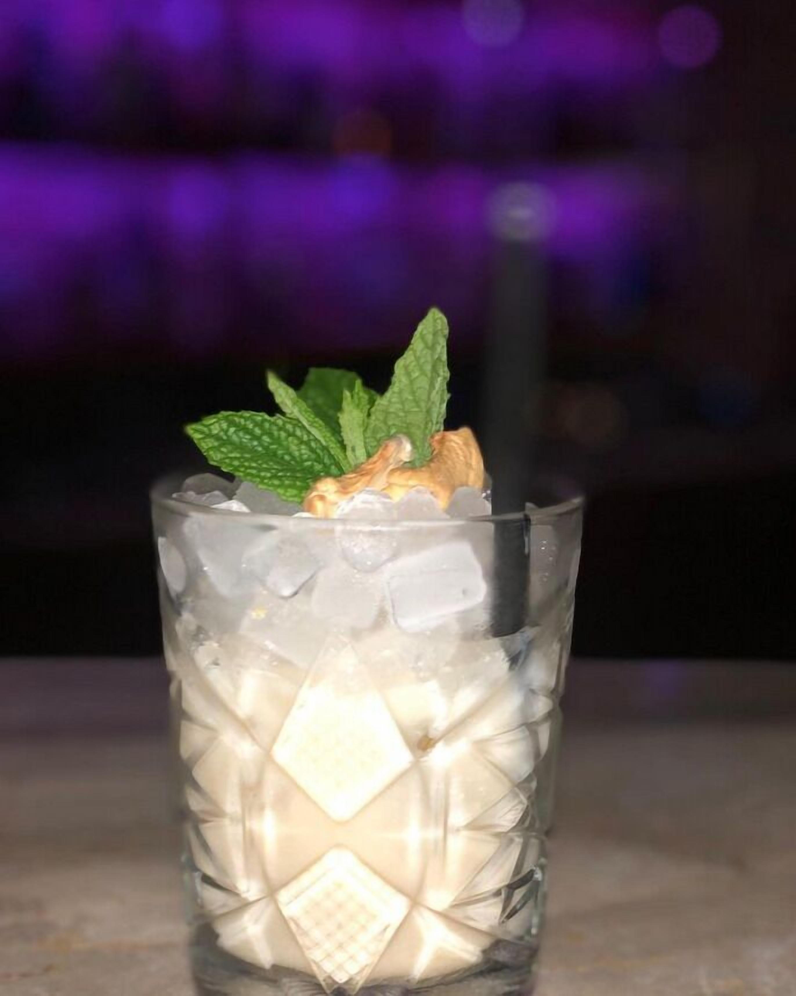 A glass with ice cubes and a mint leaf garnish.