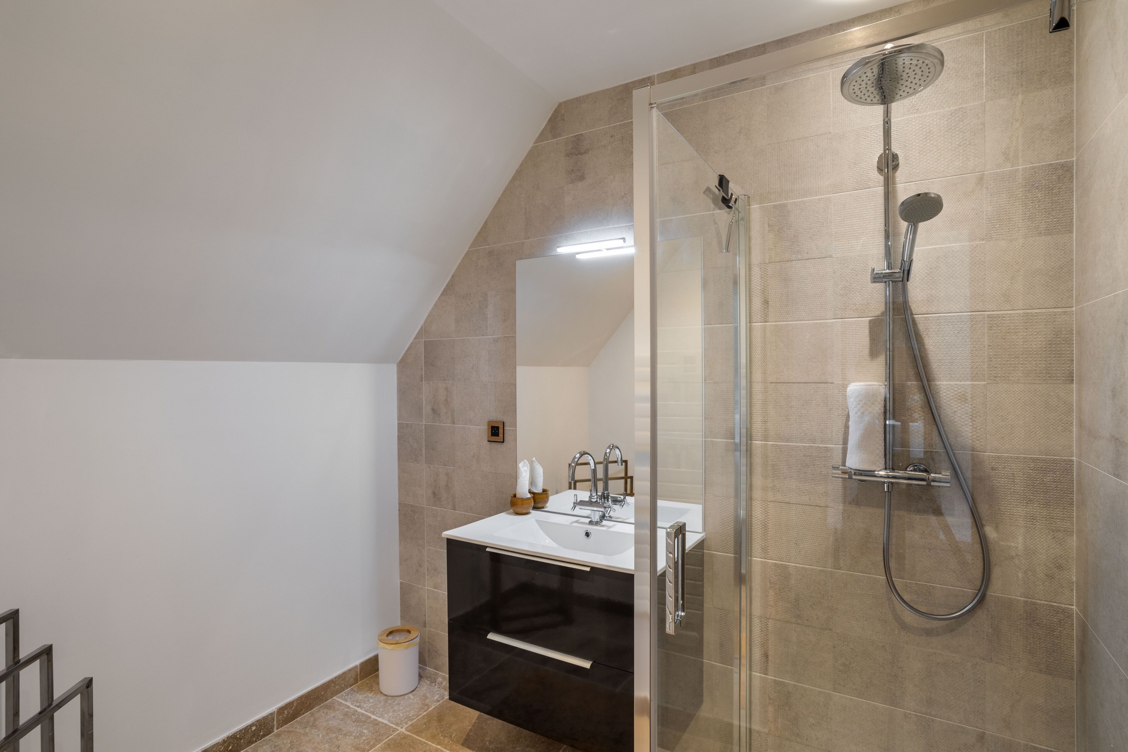 Une salle de bain moderne avec une douche à parois de verre, un lavabo blanc et un meuble noir.