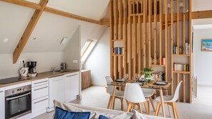 A modern loft apartment with a kitchen, dining area, and a wooden bookshelf. - Ar Chadenn - Maison d'architecte (Saint-Cast-le-Guildo)