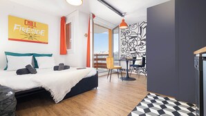 A modern bedroom with a bed, a dining table, and a view of the outdoors. - travelski home select - Résidence Yoonly & Friends - FRIENDS Studio 5 personnes (Risoul)
