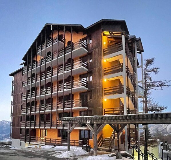 Un hôtel à plusieurs étages doté de balcons, d’un escalier et offrant une vue sur les montagnes.
