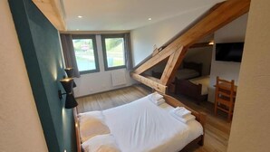 A bedroom with a sloped ceiling, a bed, a desk, and a chair. - Espace Morteau (Morteau)