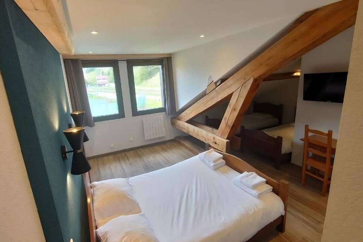 A bedroom with a sloped ceiling, a bed, a desk, and a chair.