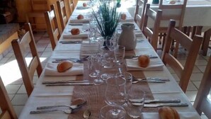 A long dining table set with multiple wine glasses, plates, and cutlery, surrounded by wooden chairs. - Espace Morteau (Morteau)