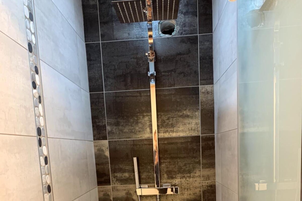Een douche met een handdouche en een bedieningspaneel aan de muur.