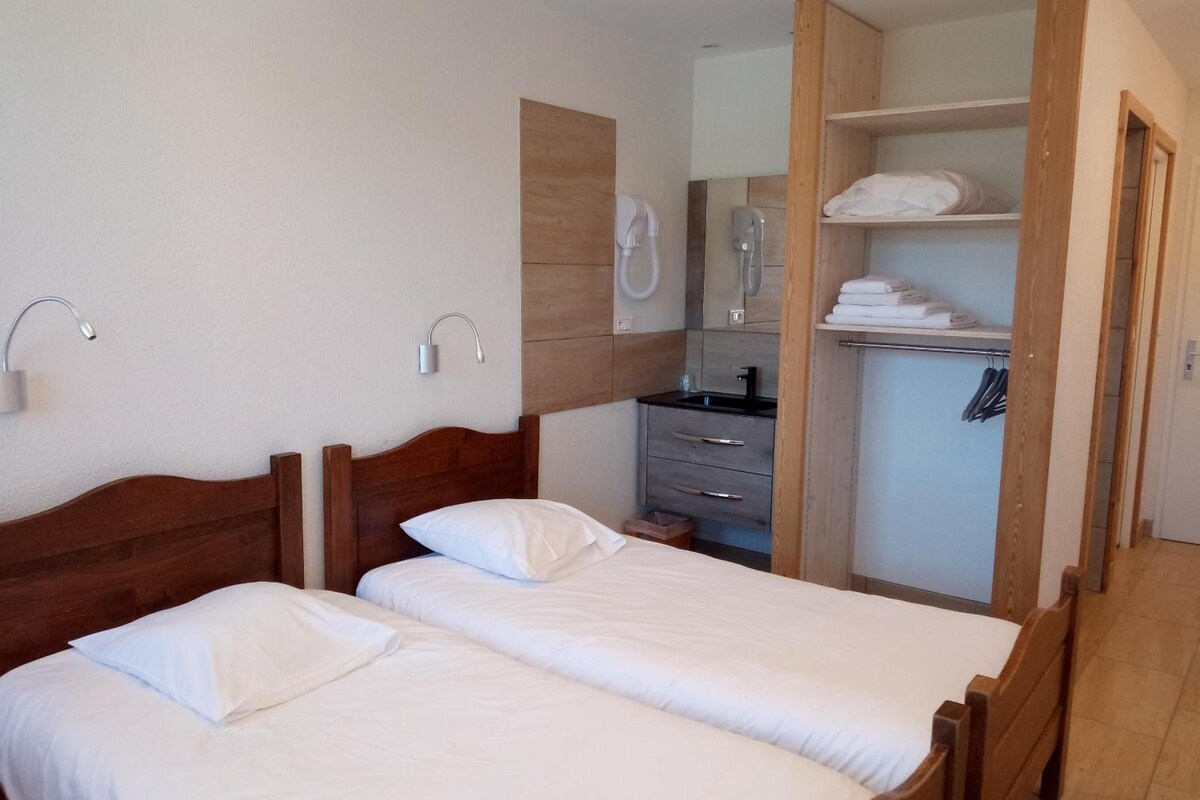 A bedroom with two wooden beds, a built-in wardrobe, and a small bathroom.