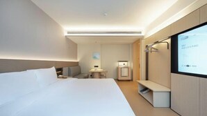 A modern hotel room with a large bed, bedside table, a small desk, a mirror, and a TV screen. - JI Hotel (Yuncheng Yanhu Tiaoshan Street) (Yuncheng)