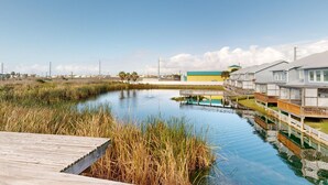 Una proprietà fronte acqua con una terrazza in legno, un canale e una fila di case con un edificio giallo e blu sullo sfondo.