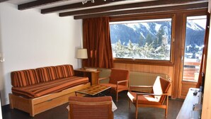 A cozy room with a sofa, chairs, a table, and a view of snow-covered mountains through large windows. - 3rd floor, balcony, tv, 64m², Pralognan-la-Vanoise (Pralognan-la-Vanoise)