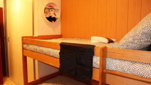 Pieni, viihtyis ä huone, jossa on kerrossänky, pyöreä hylly täynnä pehmoleluja ja kuviollinen matto.
