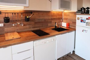 A modern kitchen with wooden countertops, a built-in dishwasher, and a black induction cooktop.