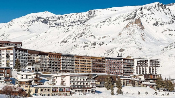 A snow-covered mountain resort with multiple buildings, including a large hotel with balconies and a ski lodge. - 150m from ski slopes, 5th floor, view lake, balcony, tv, ski locker, 50m², Tignes (Tignes)