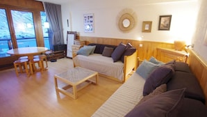 A cozy living room with a sofa, a small table, and a dining area with chairs. - 150m from ski slopes, 5th floor, view lake, balcony, tv, ski locker, 50m², Tignes (Tignes)