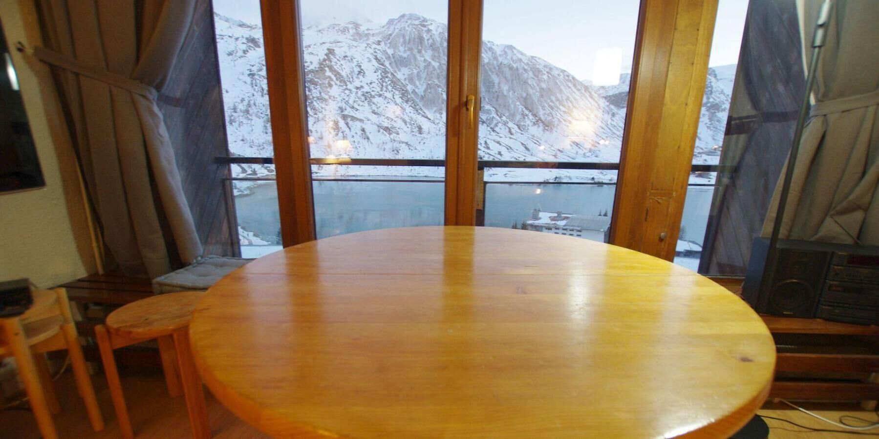 Ein Holztisch mit Blick auf verschneite Berge durch große Fenster.