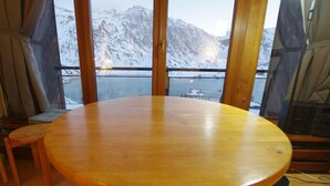 A wooden dining table with a view of snow-covered mountains through large windows. - 150m from ski slopes, 5th floor, view lake, balcony, tv, ski locker, 50m², Tignes (Tignes)