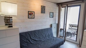 Una stanza moderna con un divano grigio, un armadietto bianco e una finestra con vista su un balcone esterno.