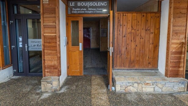 Ingresso di un edificio in legno con un cartello che riporta 