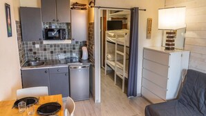 Una cucina compatta con forno a microonde, lavandino e piccolo frigorifero. C'è un tavolo da pranzo con sedie e un divano.