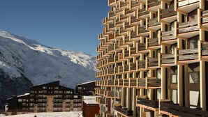 Un edificio moderno con una fachada geométrica distintiva, situado en una zona montañosa nevada.