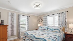 Un dormitorio con cama, mesita de noche, cómoda y ventana con cortinas.