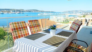 A balcony with a table and chairs, overlooking a marina with boats and a coastal town. - Luxury 90 m2 Apt.w.balcony & Spectacular sea View (Seget)