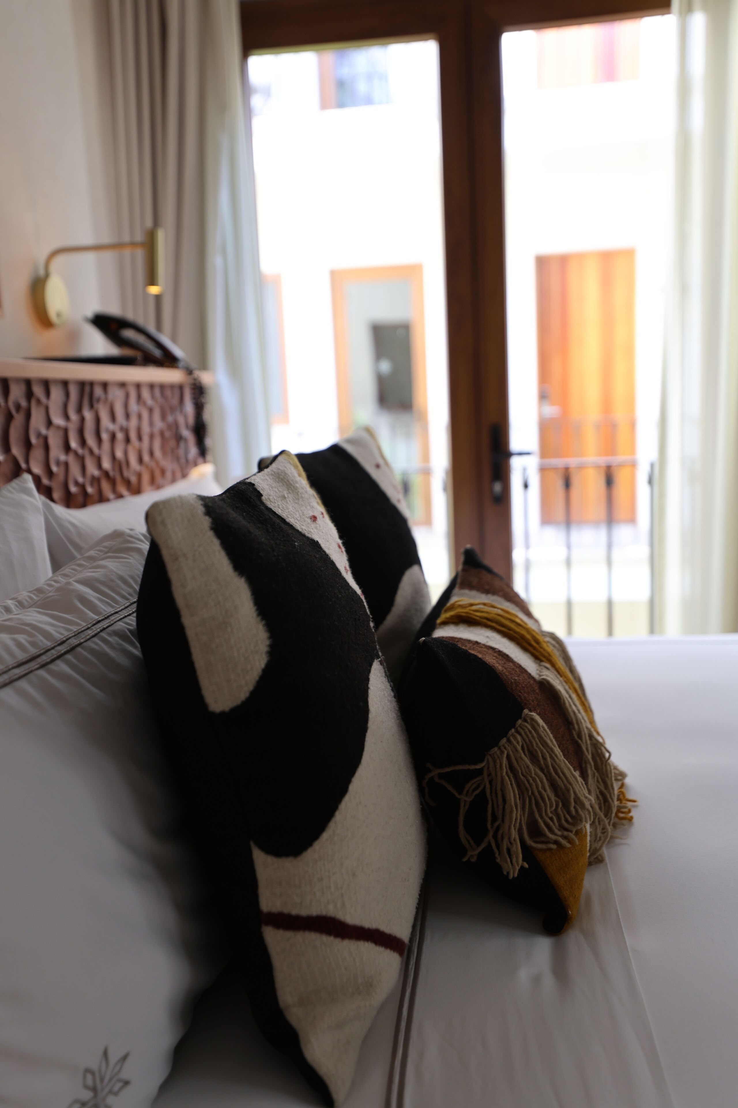 Una habitación de hotel con cama, almohadas y vistas al exterior.