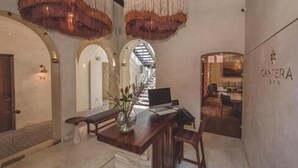Un área de recepción con un escritorio de madera, un jarrón con flores y un letrero que dice "CATERA".