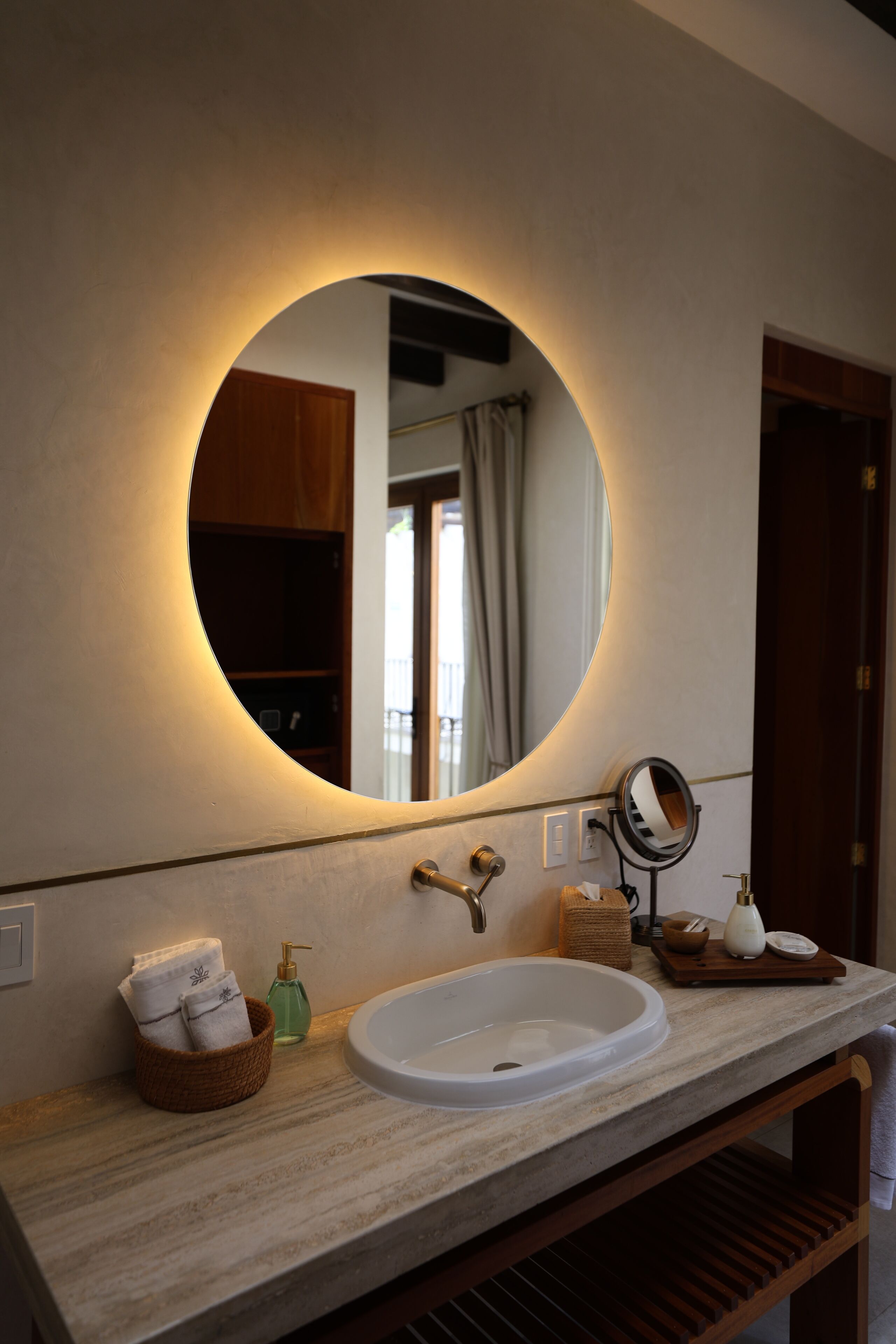 A bathroom with a round mirror, a sink, and a towel rack.