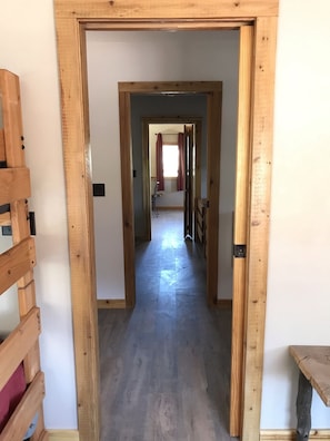 A wooden-framed hallway leading to a room with a window and a curtain.