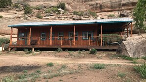 Eine Holzblockhütte mit Veranda, Fenstern und einer überdachten Terrasse.