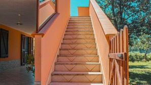 A staircase with a wooden handrail leading to an upper level. - Villetta I Pini Azzurri, with large garden and private tennis court (Sardegna)