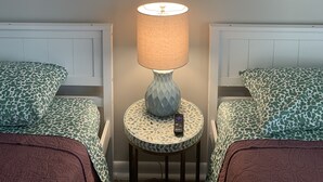 Ein Zimmer mit einem Gemälde einer Strandansicht, einer Lampe und zwei gemusterten Stühlen.