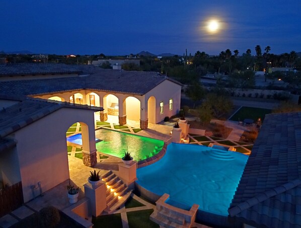 Relax by the pool surrounded by a serene garden with palm trees and distant mountain views.