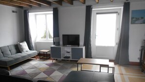 A modern living room with a grey sofa, a small table, and a TV on a stand.