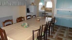A dining area with a patterned tablecloth, wooden chairs, and a central decorative item.