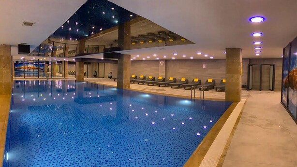 Una piscina amb sostre estrellat, gandules i un disseny arquitectònic modern.