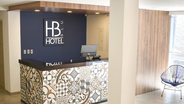 Ein moderner Hotelrezeptionstresen mit digitalem Bildschirm und einer Wand mit Musterfliesen.