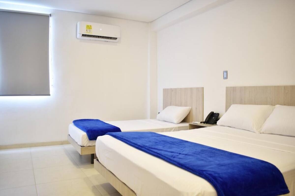 Une chambre d’hôtel avec deux lits, une fenêtre, un appareil de climatisation et un téléphone sur la table de chevet.