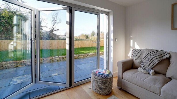 A modern living room with a sliding glass door leading to a patio area. - Elmwood (Port Isaac)