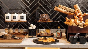Un bufé de desayuno con panes, pasteles y acompañamientos varios.