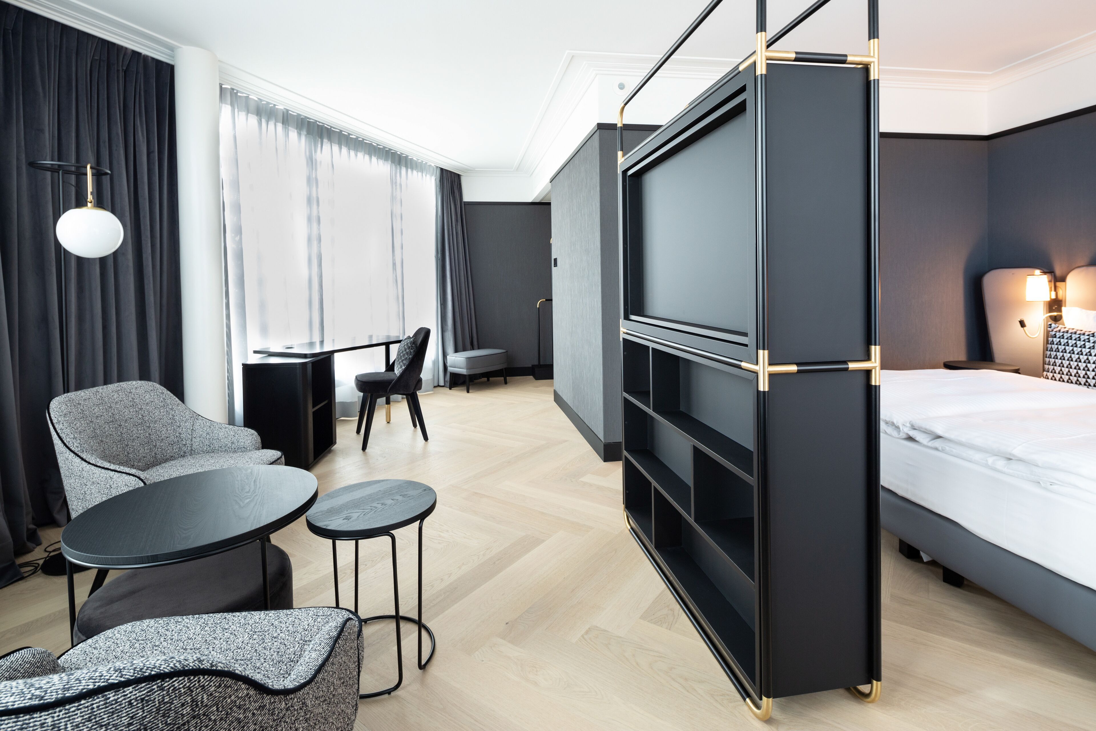 Een moderne hotelkamer met een bed, een televisie, een bureau en een zithoek.