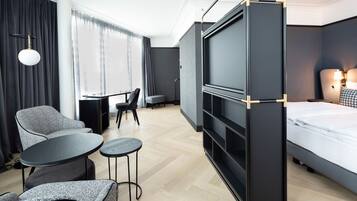 Een moderne hotelkamer met een bed, een televisie, een bureau en een zithoek.