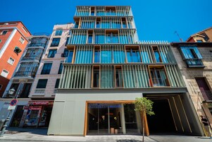 A multi-story building with a modern facade, large windows, and a visible entrance with a sign reading "AKEAH GRAN VIA".