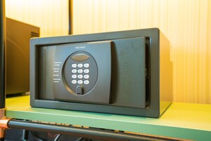 A black electronic device with a keypad, possibly a security system, on a green surface.