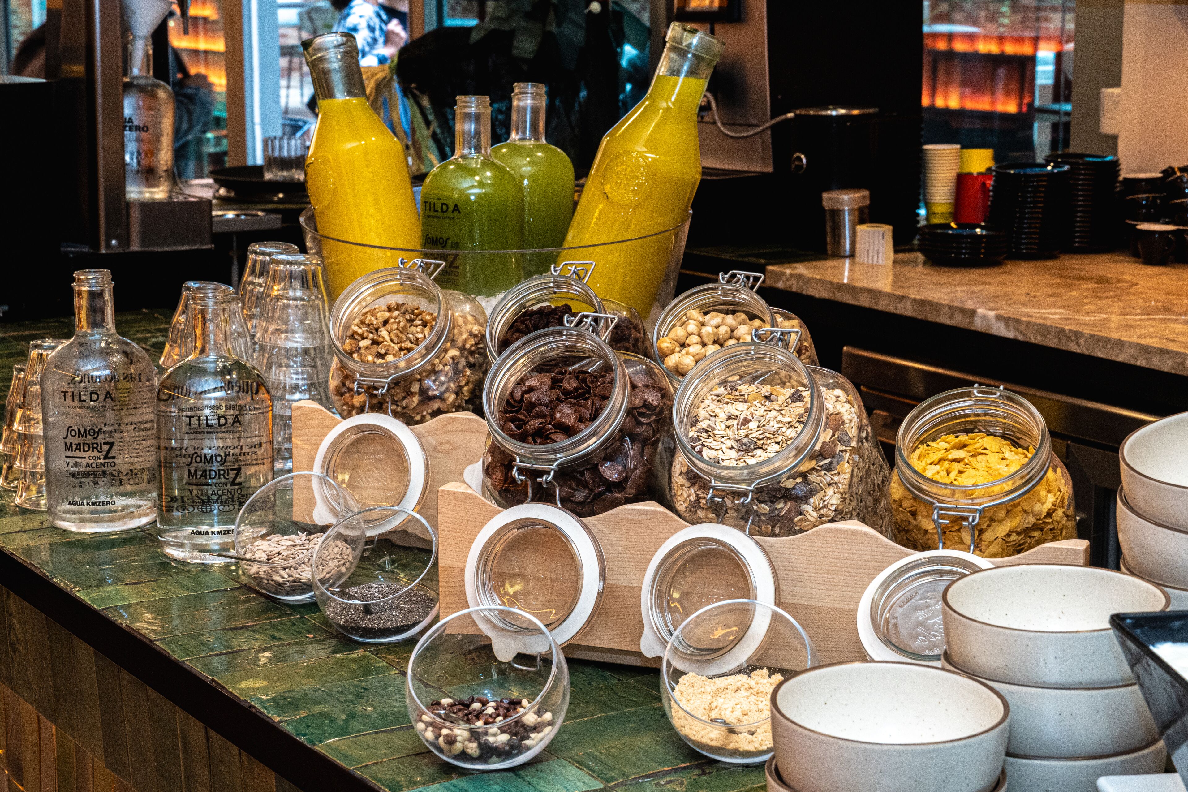 A variety of food and drink dispensers, including bottles and jars, on a counter.